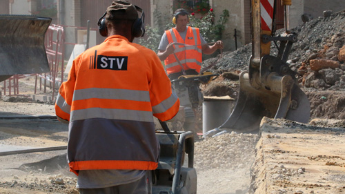 Zwei Arbeiter verschließen und verdichten einen Baustellengraben
